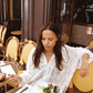 Woman in Kinga Csilla Tottori Lace Pia Mini white embroidered cotton dress sitting at a Paris café table with salad and omelette, relaxed French lifestyle outfit inspiration.