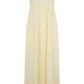 A pale cream maxi dress with thin spaghetti straps, a scalloped lace bodice, and two large patch pockets on a plain white background.