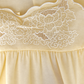 Close-up of a cream-colored fabric garment with white floral embroidery and a scalloped embroidered neckline.