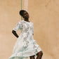 Woman wearing romantic light blue lace midi dress with back waist tie, round neckline, and airy unlined design 