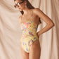 Woman wearing a colorful yellow swimsuit against a beige curtain background