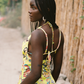 Woman in a colorful yellow dress standing outdoors with a natural background