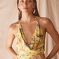 Woman wearing a yellow floral dress against a beige background