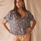 Woman wearing a colorful yellow bikini with a matching top against a beige background