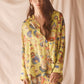 Woman wearing a yellow floral set against a beige background