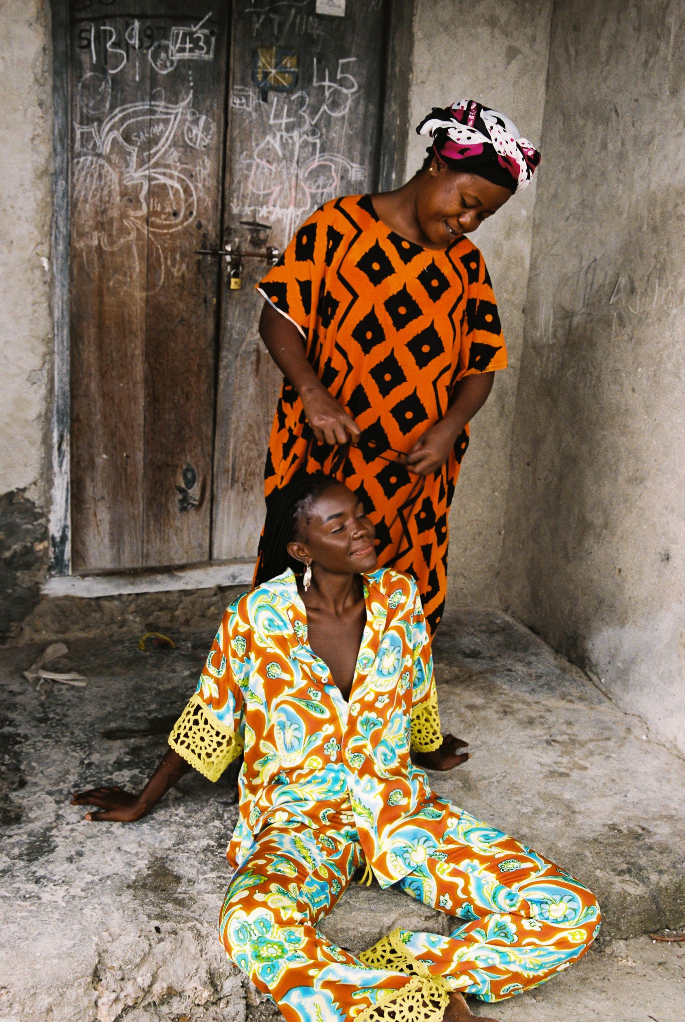 Woman wearing vibrant citrus orange, aqua and lime floral resort shirt with lime green crochet lace cuffs, slinky fabric, and relaxed oversized fit.