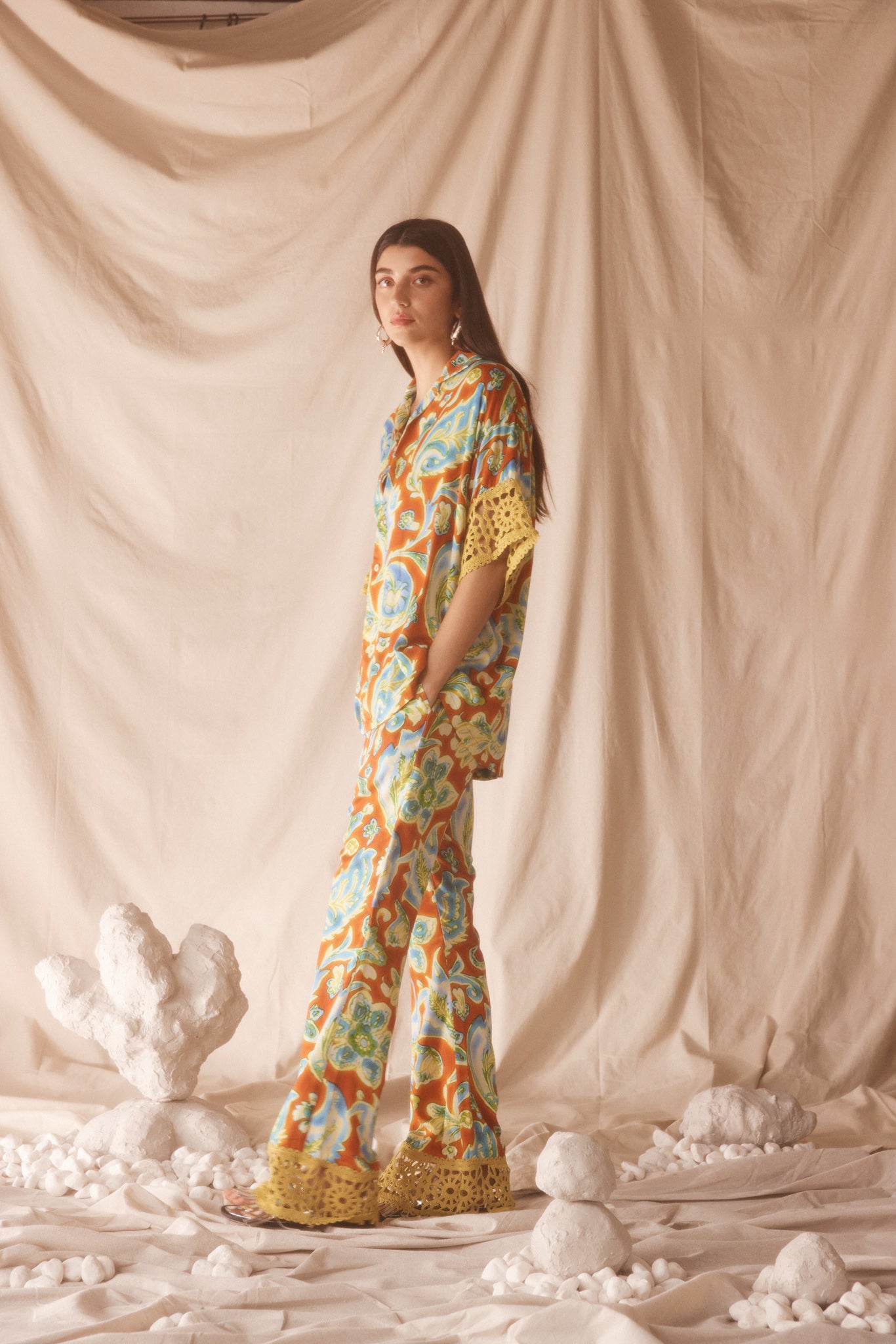 Woman wearing vibrant citrus orange, aqua and lime floral resort shirt with lime green crochet lace cuffs, slinky fabric, and relaxed oversized fit.