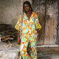 Woman wearing colourful orange, blue and green print flared pant and shirt set with green lace trim detailing