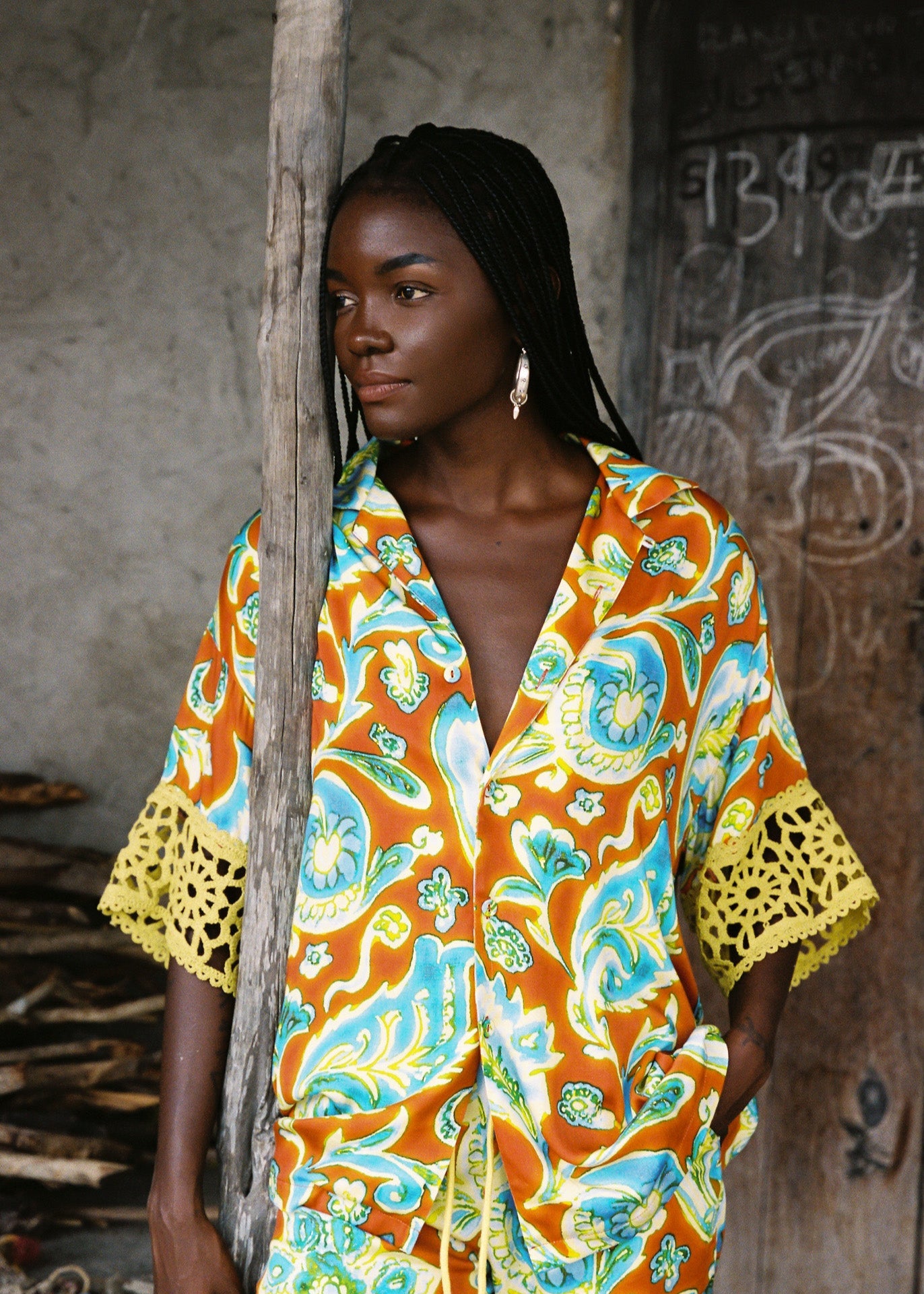 Woman wearing vibrant citrus orange, aqua and lime floral resort shirt with lime green crochet lace cuffs, slinky fabric, and relaxed oversized fit.