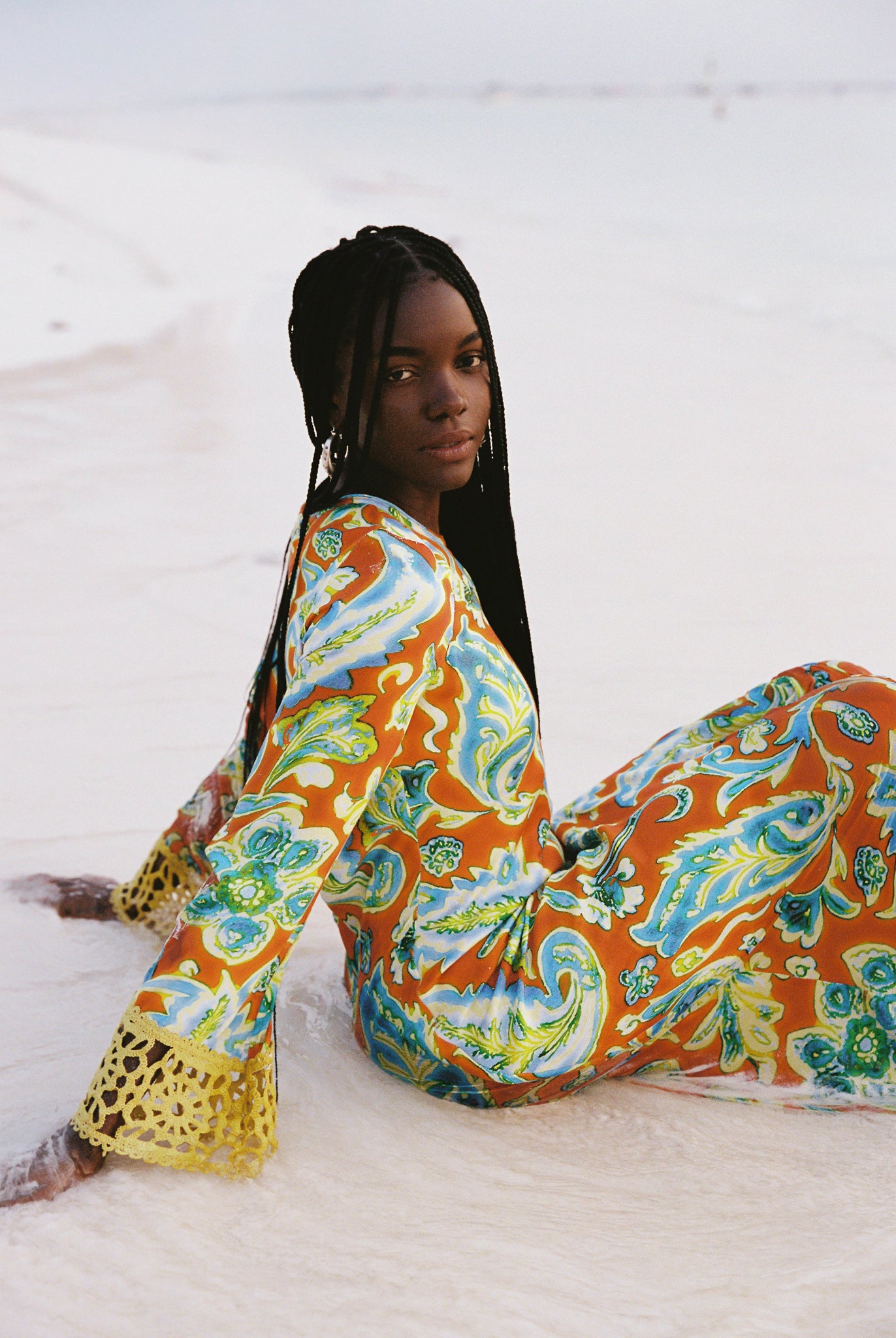 Woman wearing a colorful orange, blue and green patterned dress with lime green embroided contrast trim detail