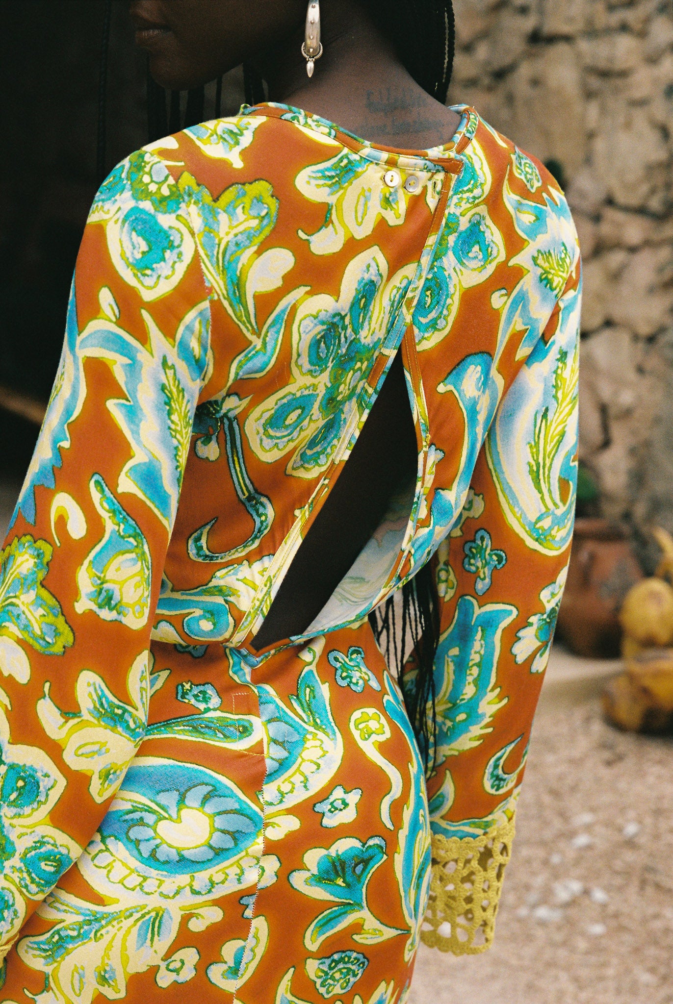 Woman wearing a colorful orange, blue and green patterned dress with lime green embroided contrast trim detail