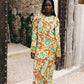 Woman wearing a colorful orange, blue and green patterned dress with lime green embroided contrast trim detail
