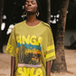 Woman wearing a lime green oversized t-shirt with colorful desert graphics and text, standing outdoors.