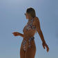 Woman in a patterned pink bikini against a clear blue sky