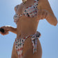 Woman wearing a pink floral bikini against a clear blue sky