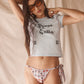 Woman wearing a graphic t-shirt and floral bikini cheeky tie pink bottom against a beige background