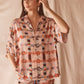 Woman wearing a pink patterned shirt and pants against a beige background