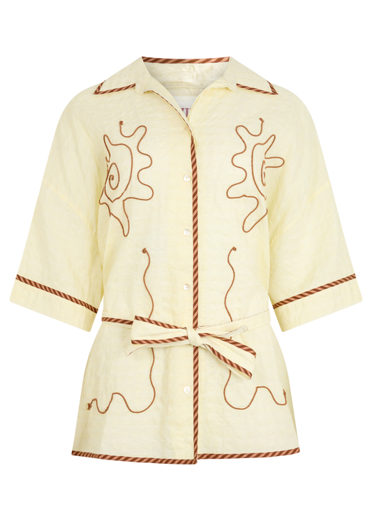 A kimono style cream shirt with brown embroidered details, displayed on a plain white background
