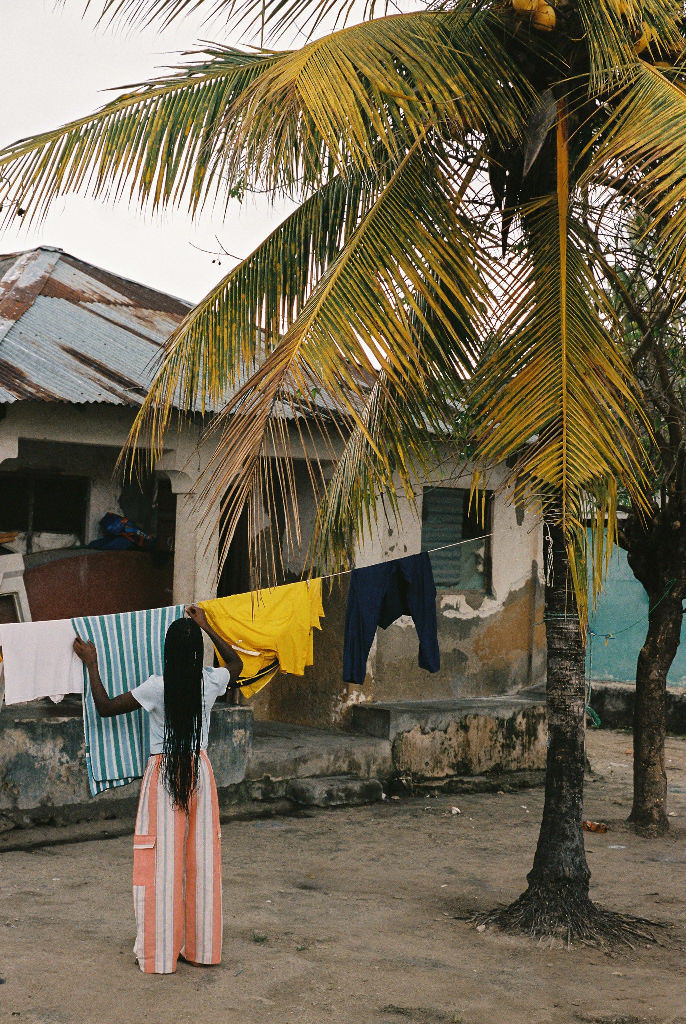 Woman wearing linen-cotton wide leg pants in peach, blue and ivory coastal stripes with side pockets and elastic waistband.