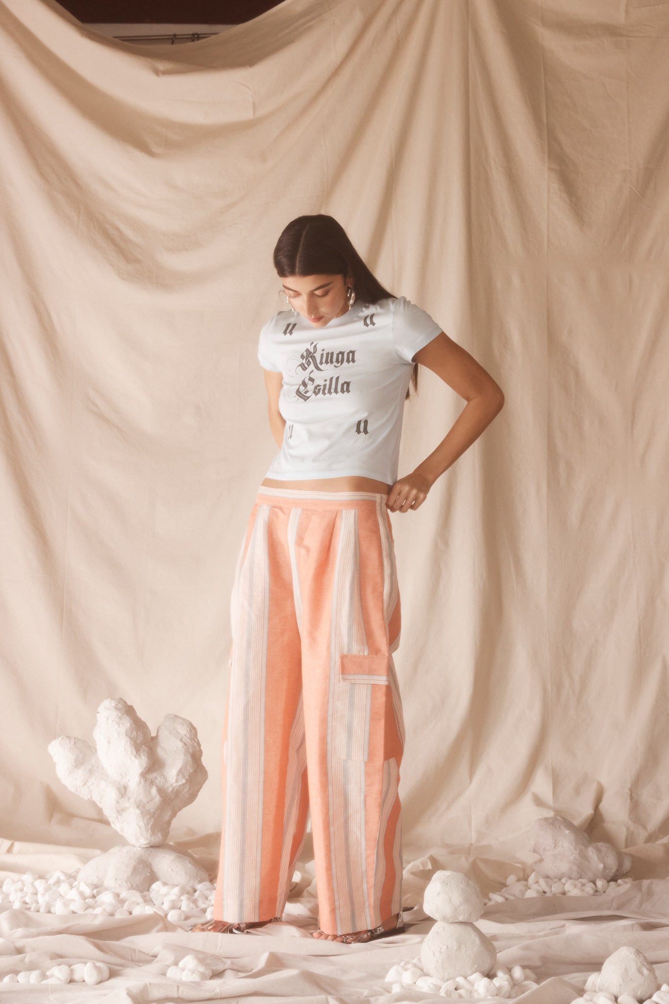 Woman wearing linen-cotton wide leg pants in peach, blue and ivory coastal stripes with side pockets and elastic waistband.
