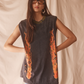 Woman wearing a sleeveless black top with orange flame patterns against a beige background