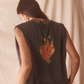 Person wearing a black sleeveless tank shirt with a colorful flame design on the back against a plain background
