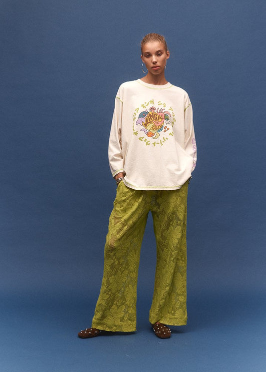 Person wearing a white sweatshirt with colorful design and green pants on a blue background