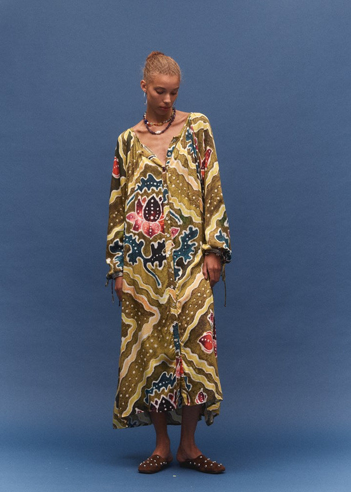 Woman wearing a colorful patterned dress against a blue background