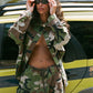 Person wearing a camouflage outfit in front of a vehicle