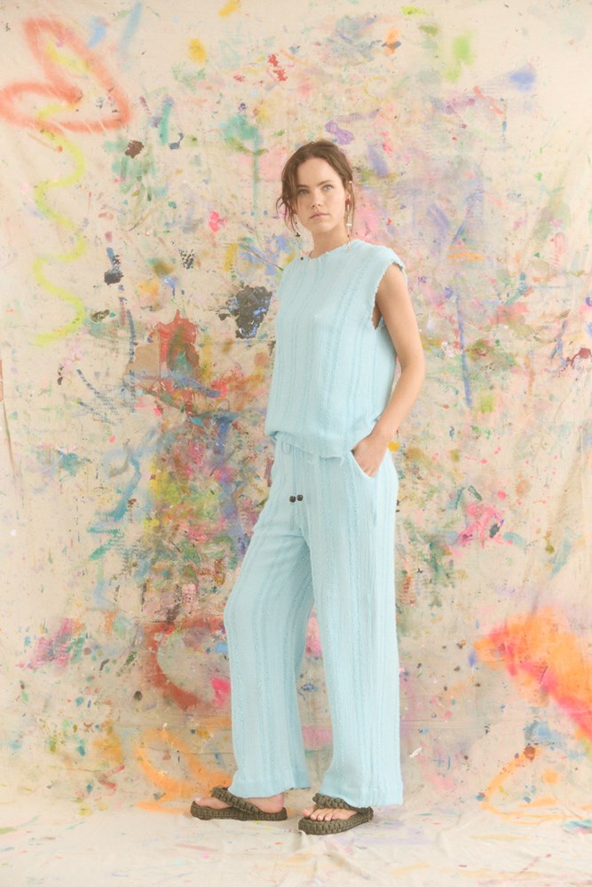 Woman in a light blue outfit standing against a colorful abstract wall.