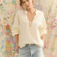 Woman wearing a white blouse and denim shorts against a colorful abstract background