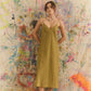 Woman in a yellow dress standing against a colorful abstract wall.