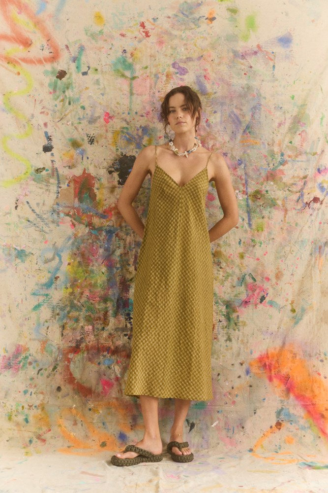 Woman in a yellow dress standing against a colorful abstract wall.