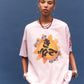 Person wearing a pink t-shirt with a colorful graphic design on a blue background