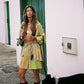 Woman in a colorful button up shirt with matching shorts.
