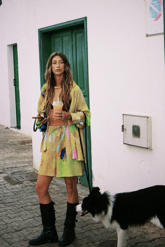Woman in a colorful button up shirt with matching shorts.