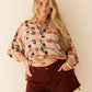 Woman wearing a patterned shirt and maroon shorts against a plain background