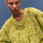 Woman wearing a bright yellow lace sweater against a blue background