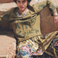 Person wearing a patterned outfit sitting on stone steps.