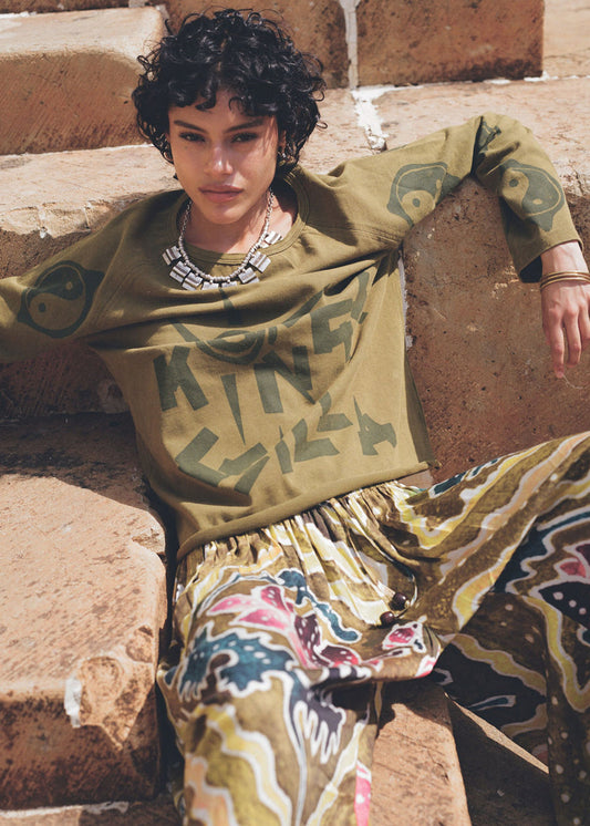 Person wearing a patterned outfit sitting on stone steps.