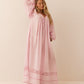 Woman wearing a pink long dress with lace details on a beige background