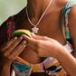 Person wearing a colorful bikini with a necklace, holding a yellow object.