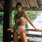 Woman in a colorful bikini standing on a wooden deck with a natural background