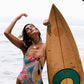 Woman in a colorful swimsuit holding a surfboard on a beach