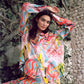 Woman wearing a colorful dress with abstract patterns in an outdoor setting.