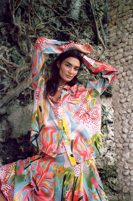 Woman wearing a colorful dress with abstract patterns in an outdoor setting.