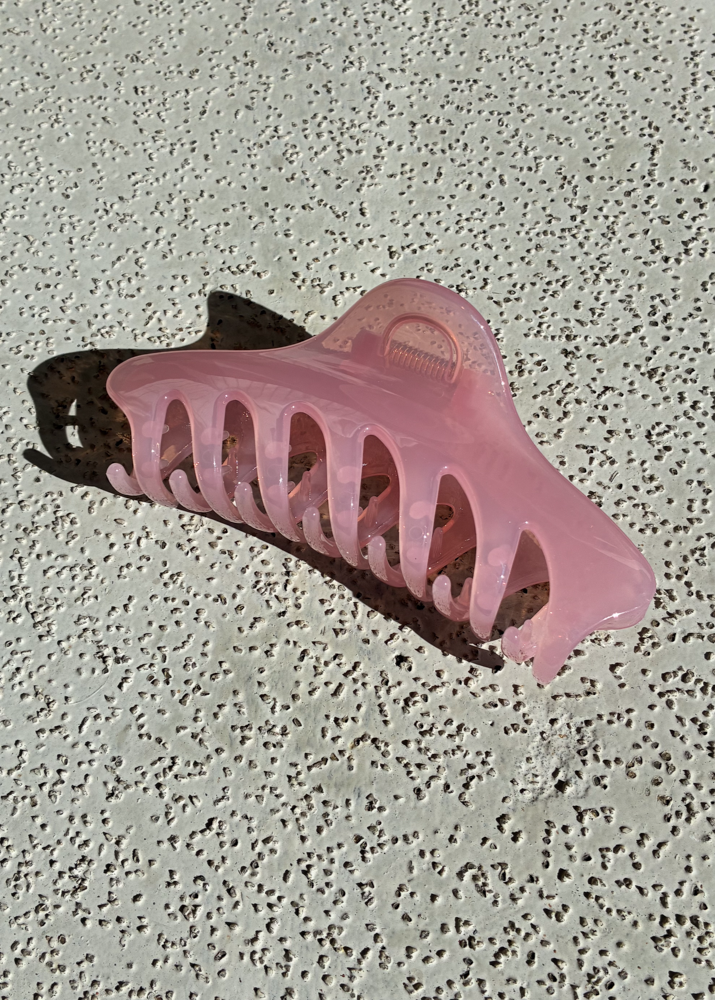 Pink claw clamp on a textured gray surface
