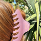 Person with pink claw clip in hair against a natural background