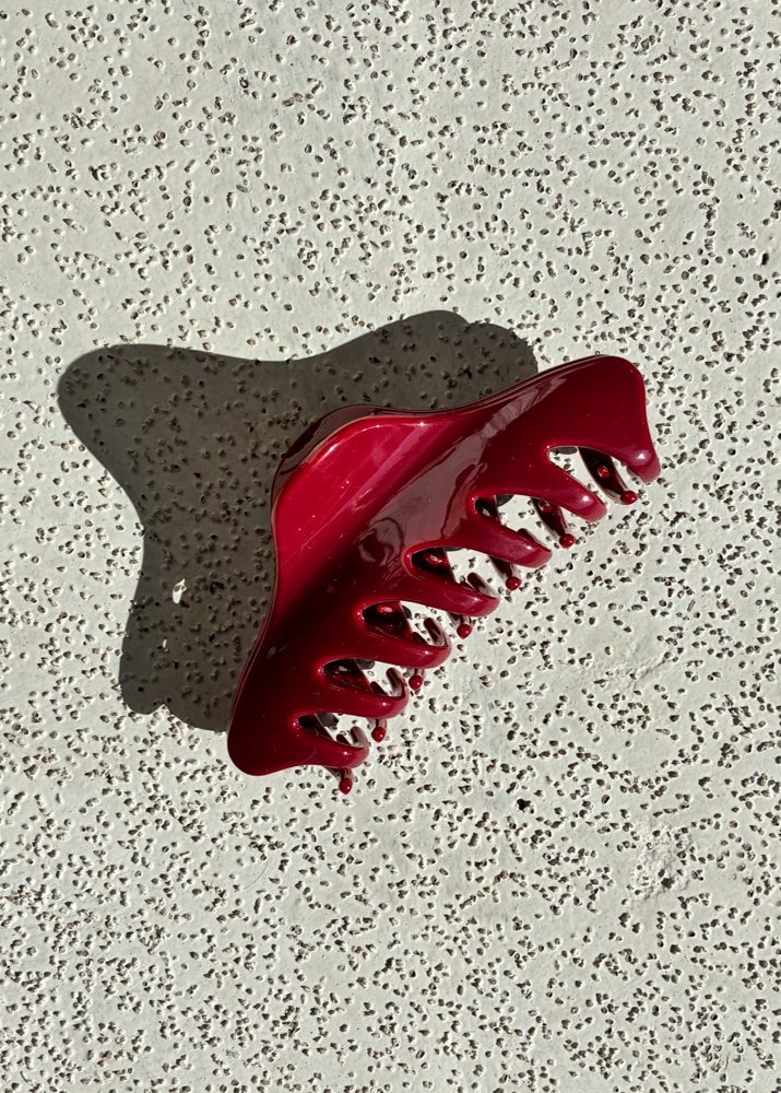 Red claw clip on a textured gray surface