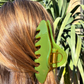 Green claw clip on a person's hair with a natural background